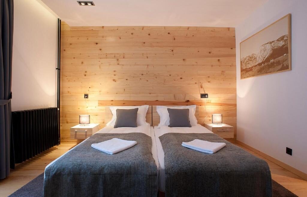 Twin beds against a wooden wall with reading lamps